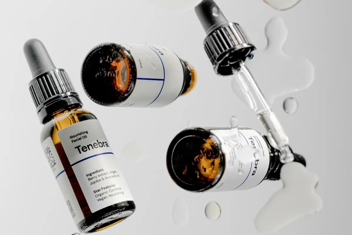 Close-up of amber glass dropper bottles and skincare packaging with water droplets, representing Selfnamed's private label cosmetics.