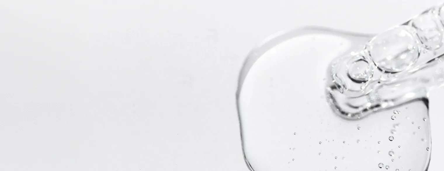 Macro close-up of a clear gel skincare texture with bubbles and droplets on a soft lavender background.
