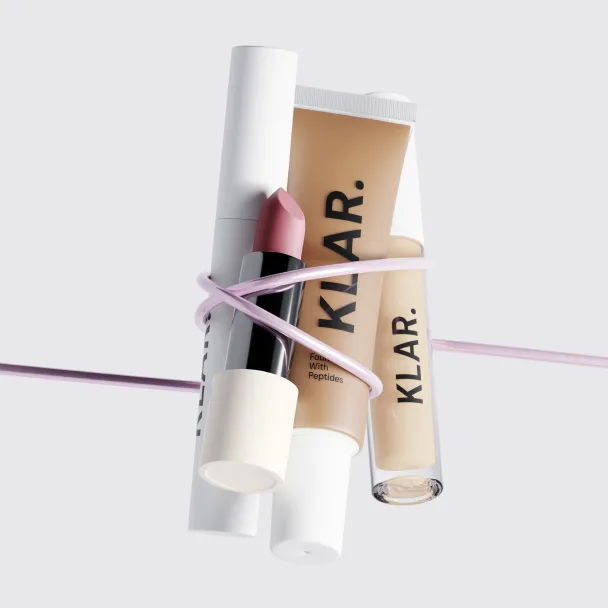 Klar-branded lip balm and gloss tubes tied together with a pink ribbon.