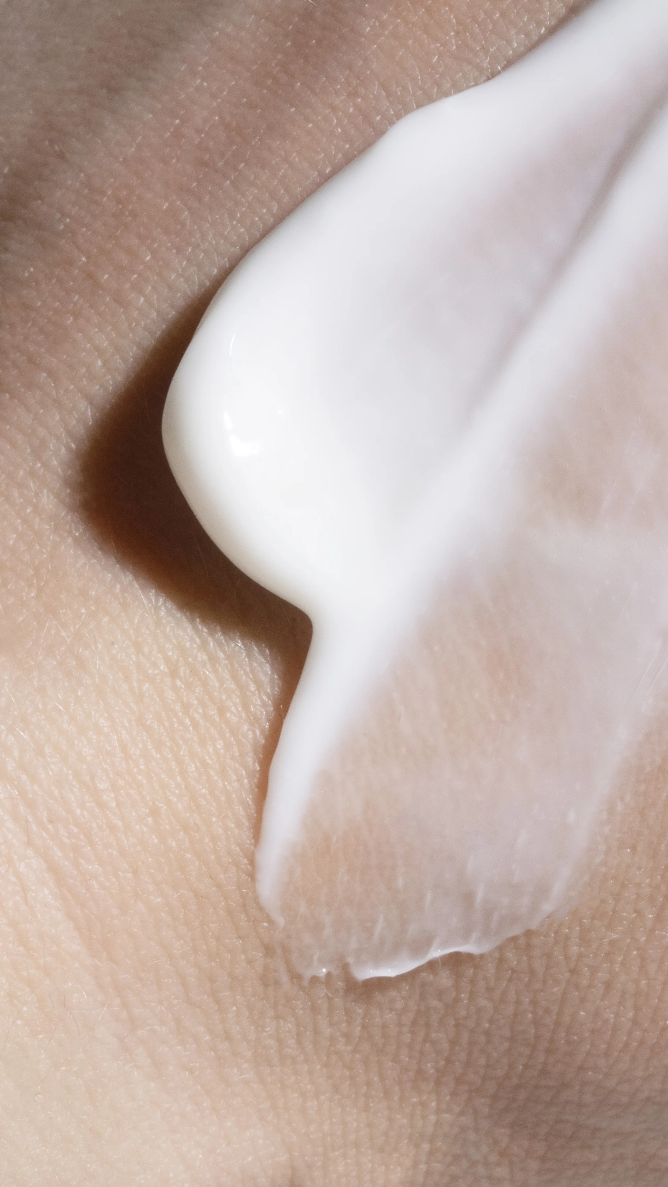 Macro shot of white lotion swirled on skin.