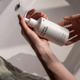 Hand holding a white pump-bottle skincare product.