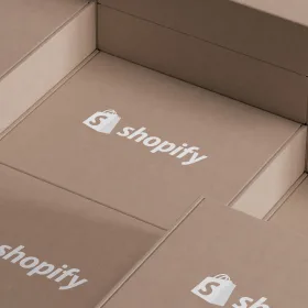 Open cardboard shipping boxes printed with the Shopify bag logo.