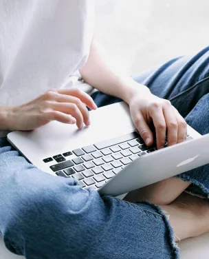 Person sitting cross-legged and typing on a laptop.